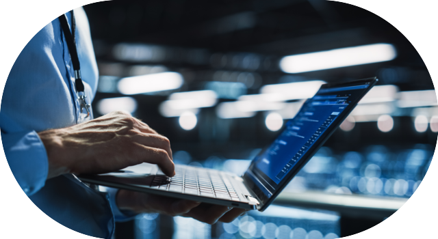 Technicien informatique consultant des données sur son ordinateur portable dans une salle de serveurs